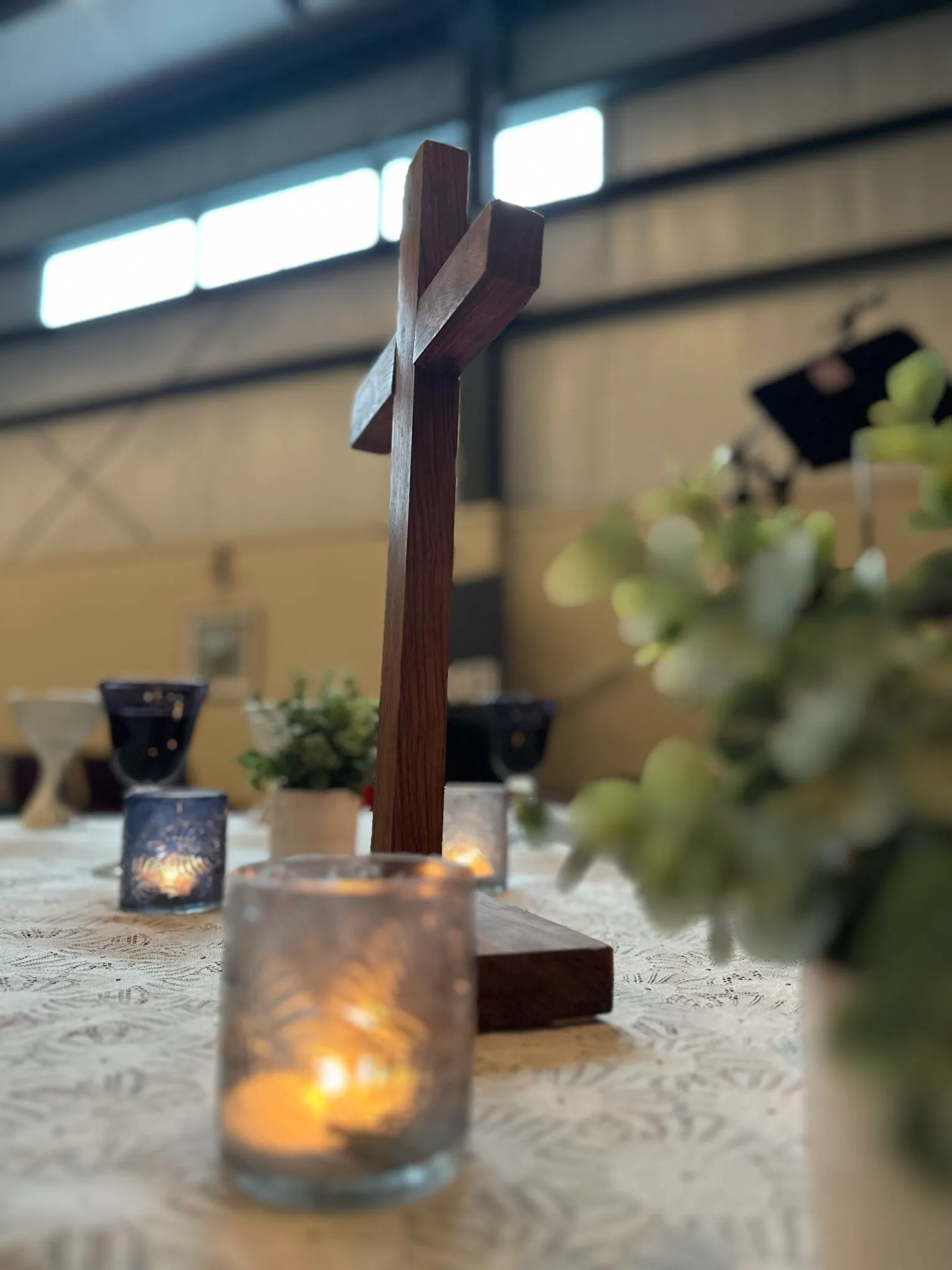 A wooden cross and candle on a worship table